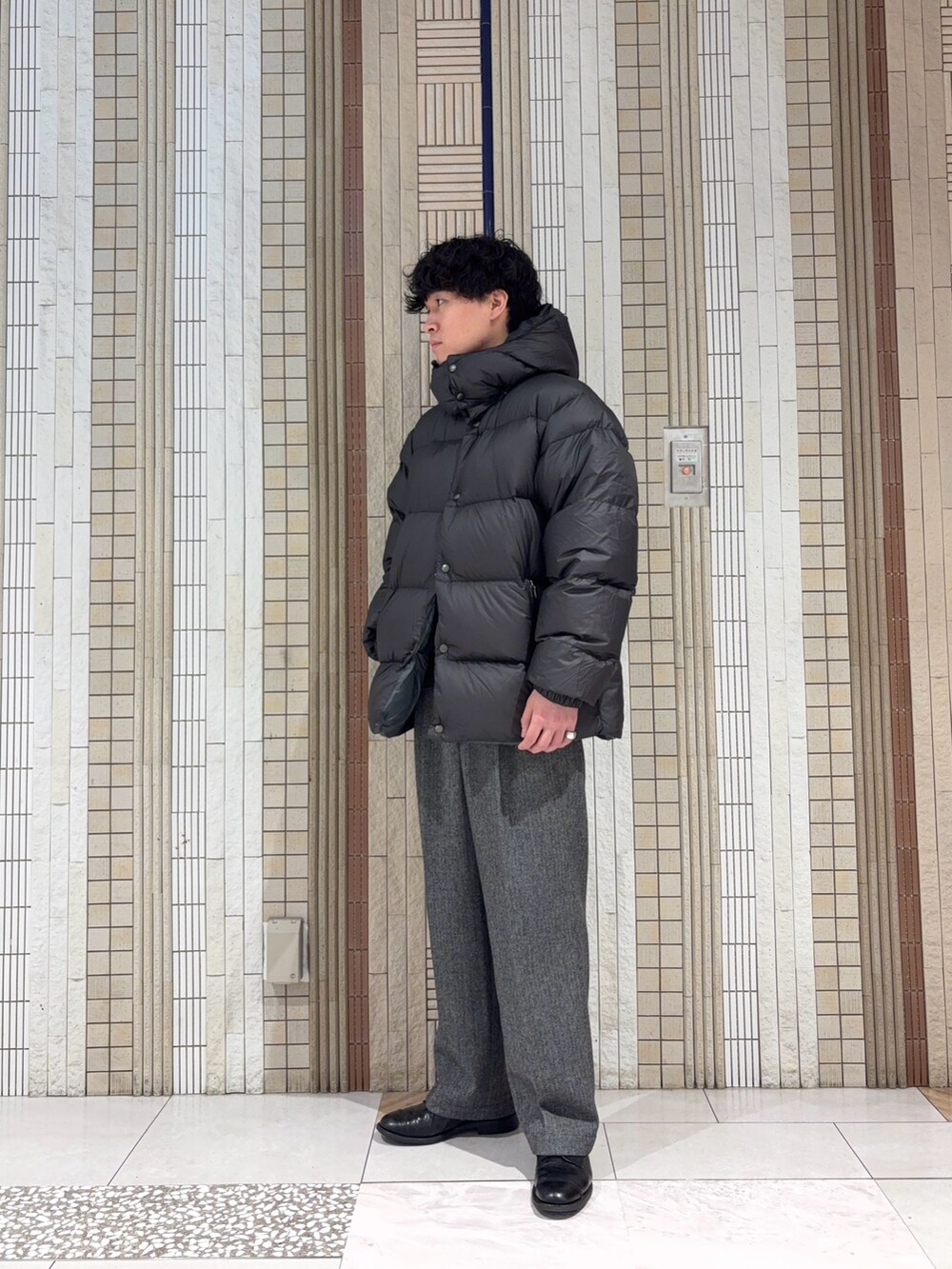 グリーン系のダウンジャケット/コート、ブラック系のニット/セーター、グレー系のその他パンツを着用したメンズの冬コーディネートの2枚目の写真