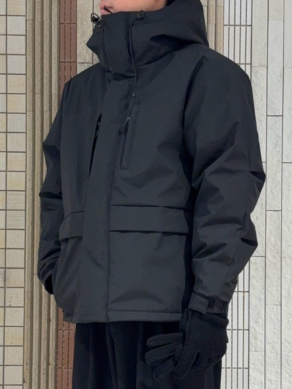 ブラック系のダウンジャケット/コート、グレー系のニット/セーター、ブラック系の手袋を着用したメンズの冬コーディネートの4枚目の写真