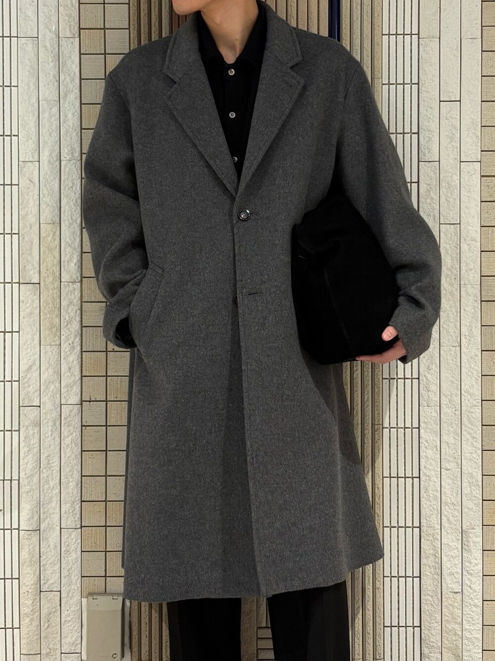 ホワイト系のチェスターコート、グリーン系のトートバッグ、ブラック系のその他パンツを着用したメンズの冬コーディネートの4枚目の写真