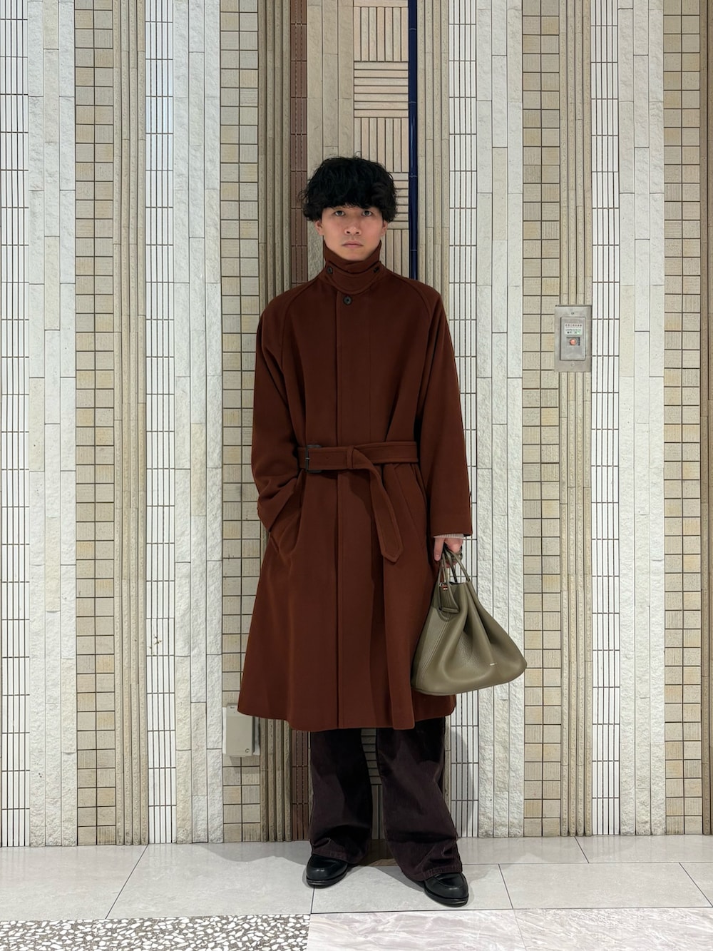 ブラウン系のステンカラーコート、ホワイト系のニット/セーター、ベージュ系のその他雑貨を着用したメンズの冬コーディネートの2枚目の写真