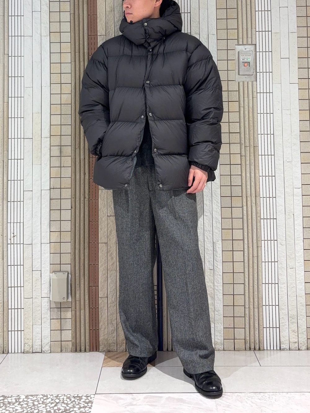 グリーン系のダウンジャケット/コート、ブラック系のニット/セーター、グレー系のその他パンツを着用したメンズの冬コーディネートの3枚目の写真