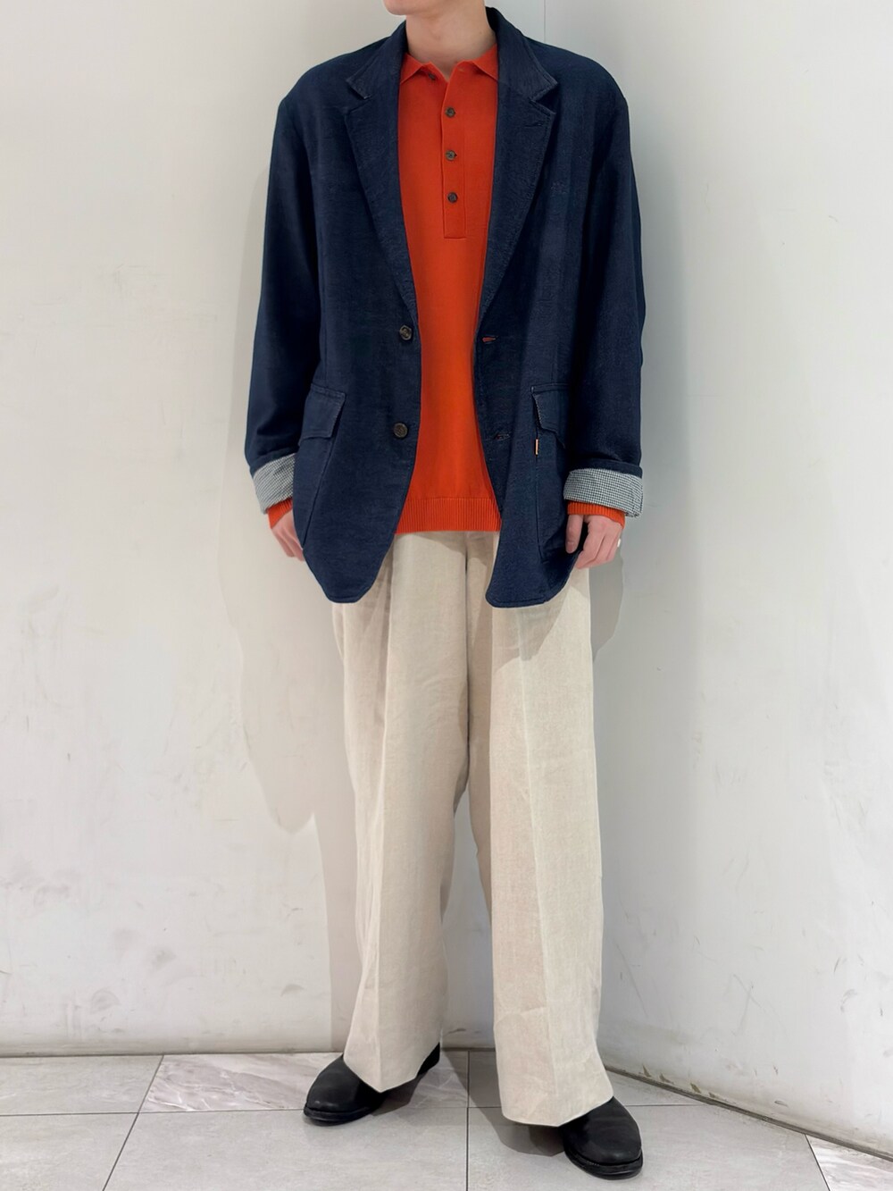 ブルー系のテーラードジャケット、オレンジ系のニット/セーター、ベージュ系のその他パンツを着用したメンズの春コーディネートの2枚目の写真