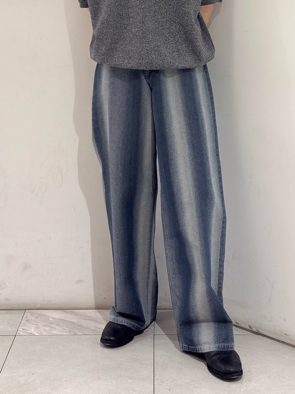 グレー系のニット/セーター、ブルー系のデニムパンツ、ブラック系のブーツを着用したメンズの春コーディネートの3枚目の写真