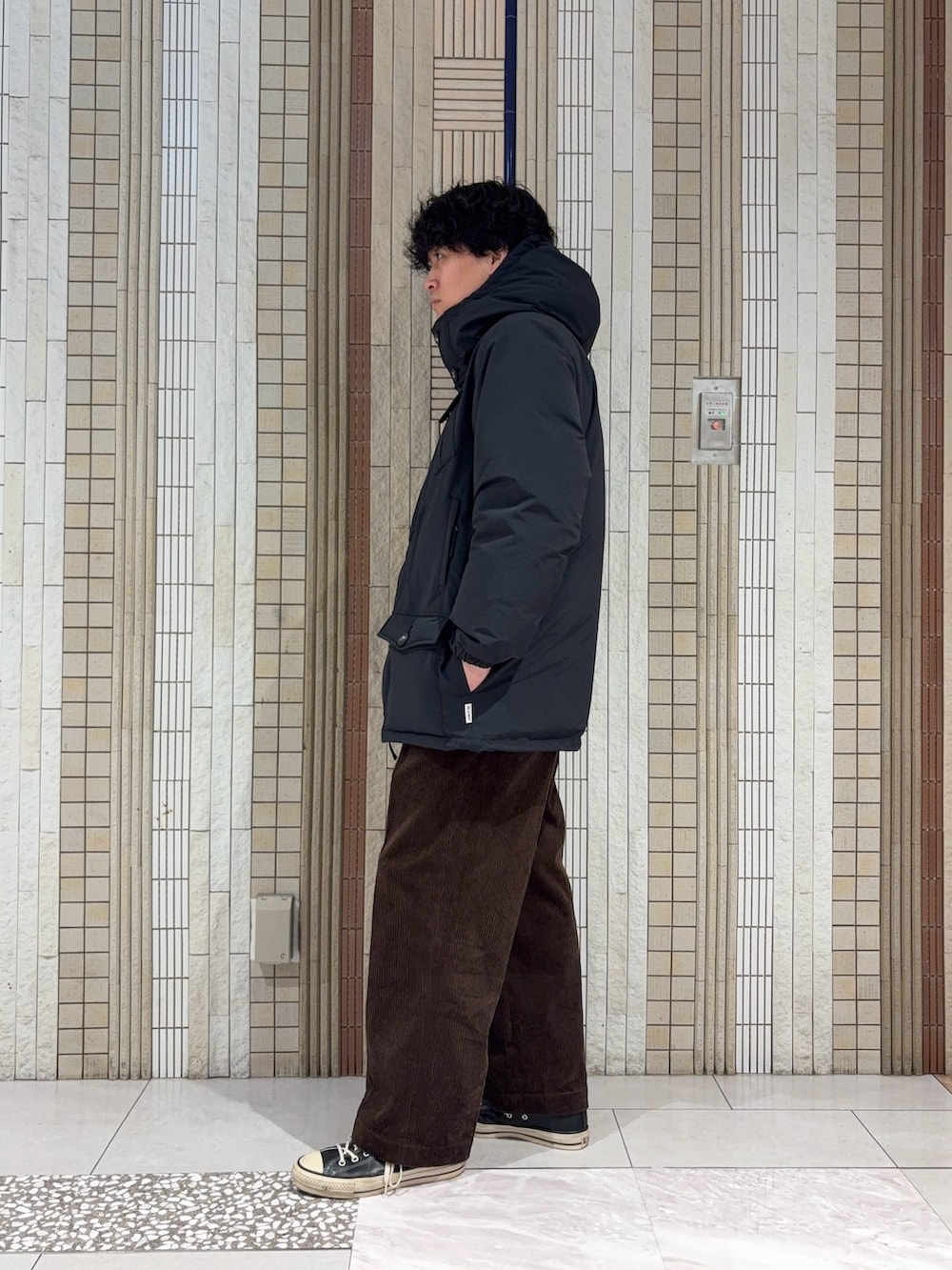 ブラック系のダウンジャケット/コート、ブラック系のニット/セーター、ブラウン系のその他パンツを着用したメンズの冬コーディネートの6枚目の写真