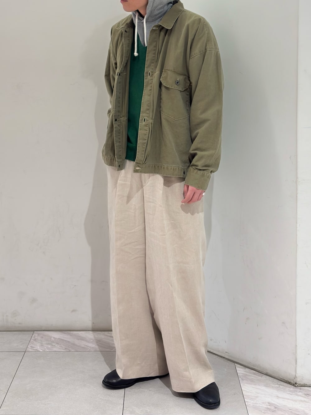 グリーン系のブルゾン、ブラック系のブーツを着用したメンズの春コーディネートの2枚目の写真