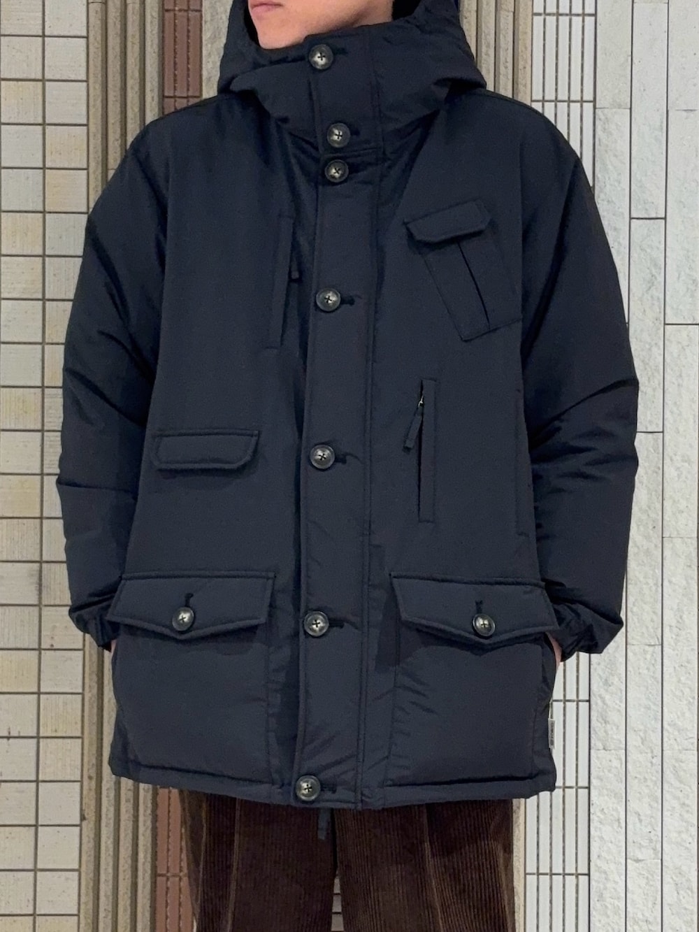 ブラック系のダウンジャケット/コート、ブラック系のニット/セーター、ブラウン系のその他パンツを着用したメンズの冬コーディネートの4枚目の写真