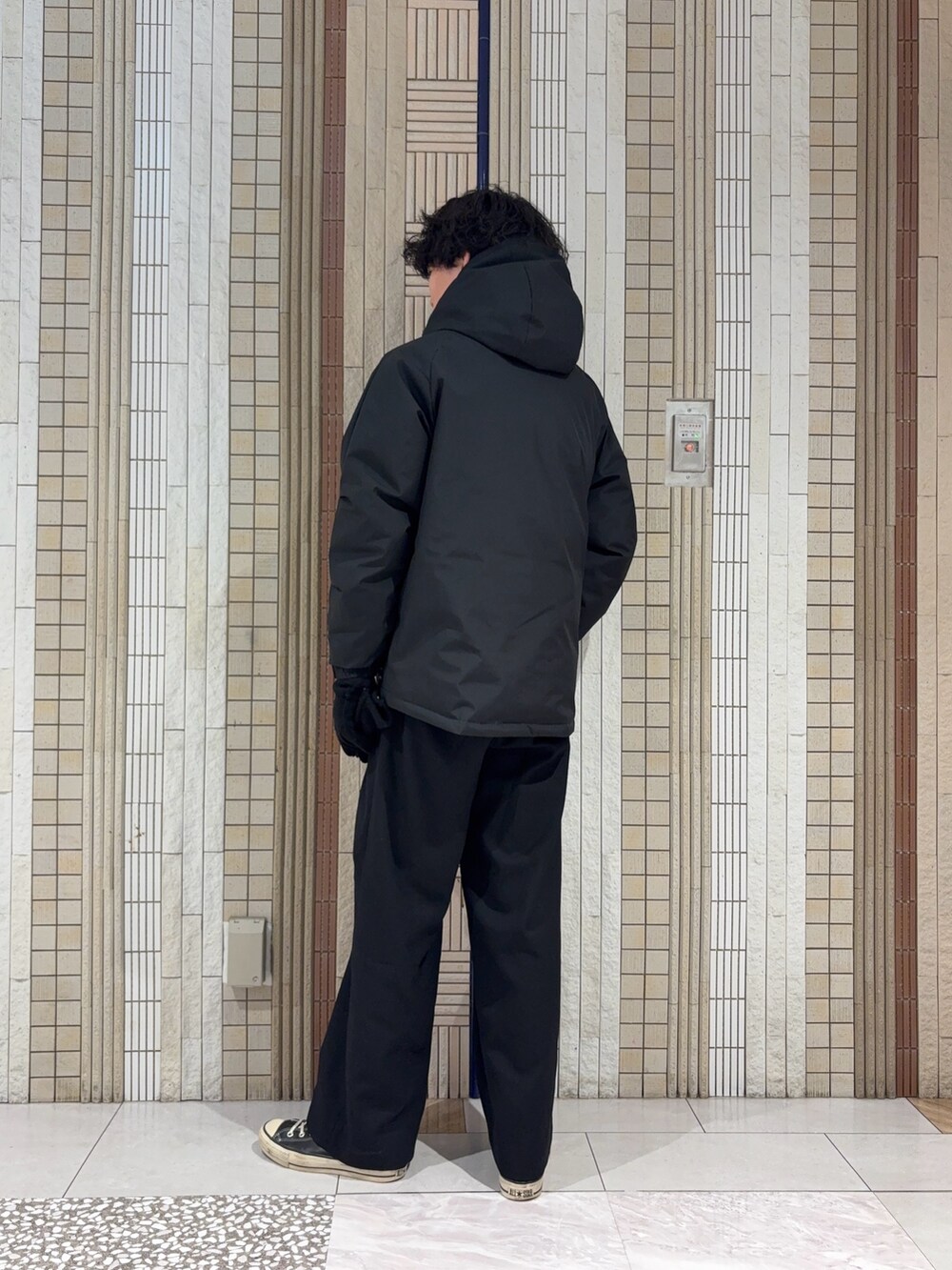 ブラック系のダウンジャケット/コート、グレー系のニット/セーター、ブラック系の手袋を着用したメンズの冬コーディネートの7枚目の写真