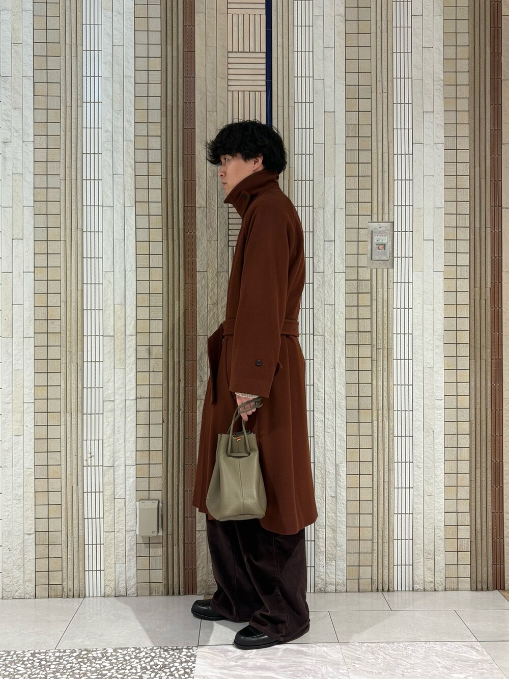 ブラウン系のステンカラーコート、ホワイト系のニット/セーター、ベージュ系のその他雑貨を着用したメンズの冬コーディネートの6枚目の写真
