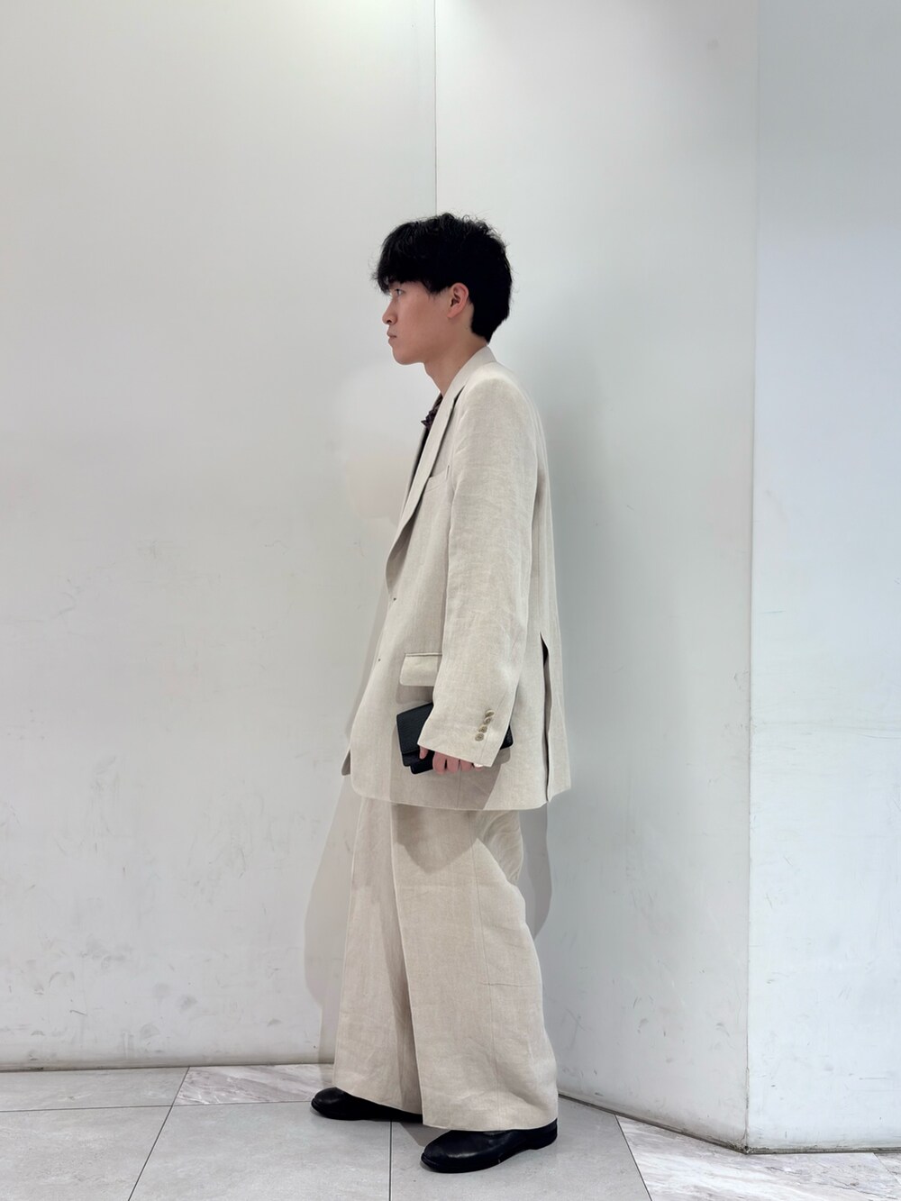 ブラウン系のニット/セーター、ベージュ系のその他パンツ、ブラック系のブーツを着用したメンズの春コーディネートの4枚目の写真