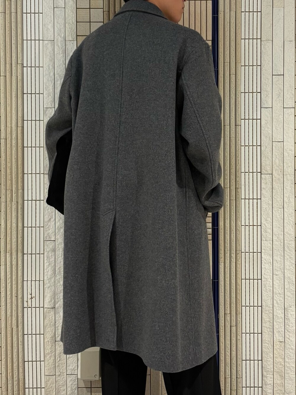 ホワイト系のチェスターコート、グリーン系のトートバッグ、ブラック系のその他パンツを着用したメンズの冬コーディネートの7枚目の写真