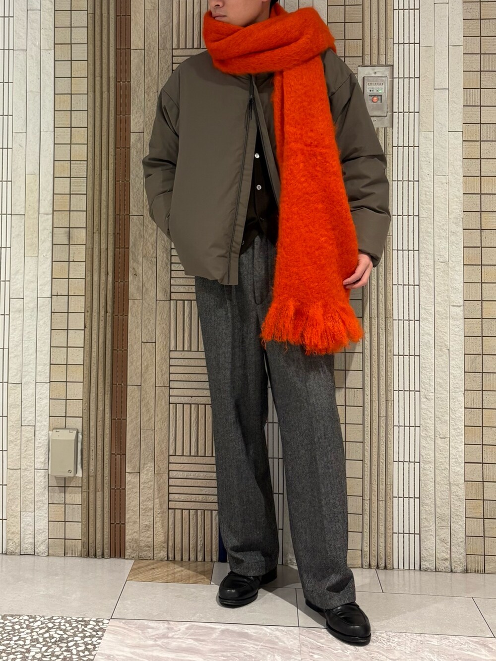 ベージュ系のダウンジャケット/コート、ブラウン系のニット/セーター、グレー系のその他パンツを着用したメンズの秋コーディネートの2枚目の写真