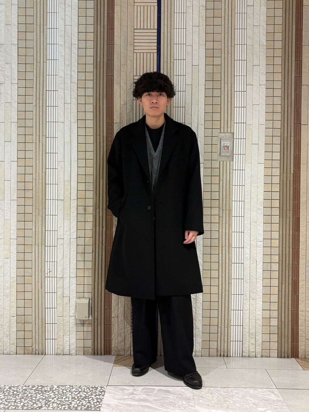 ブラック系のチェスターコート、グレー系のカーディガン/ボレロを着用したメンズの冬コーディネートの2枚目の写真