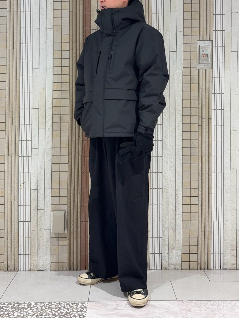 ブラック系のダウンジャケット/コート、グレー系のニット/セーター、ブラック系の手袋を着用したメンズの冬コーディネートの3枚目の写真