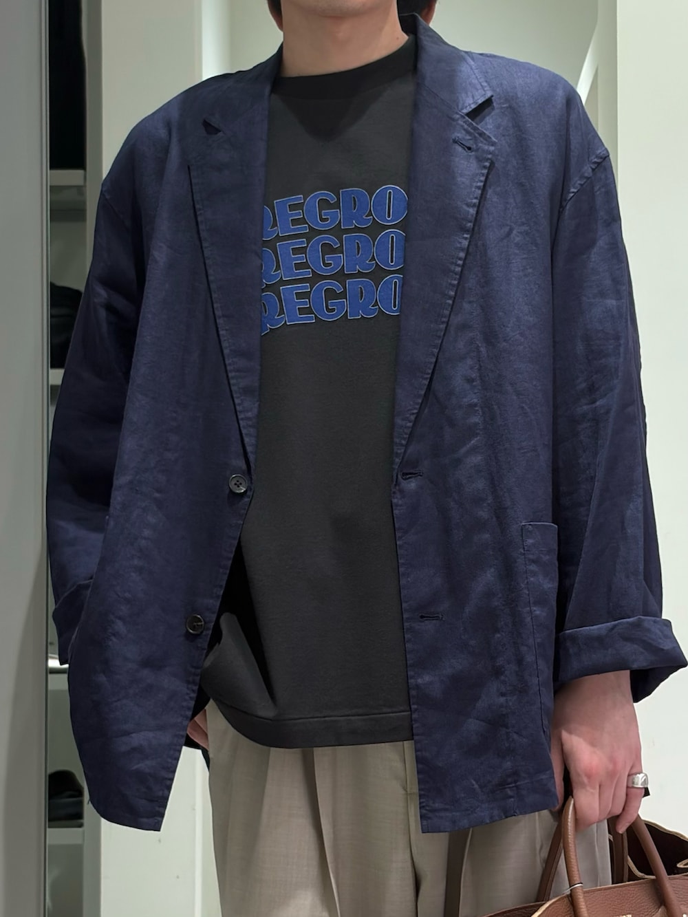 ブルー系のその他アウター、ベージュ系のその他パンツ、ブラウン系のトートバッグを着用したメンズの春コーディネートの3枚目の写真
