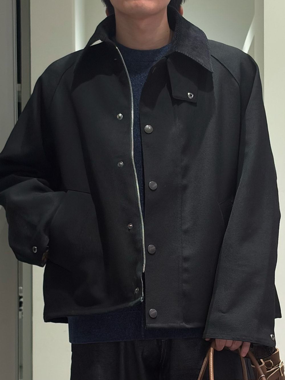ブラック系のその他アウター、ブルー系のニット/セーター、ブルー系のデニムパンツを着用したメンズの秋コーディネートの3枚目の写真