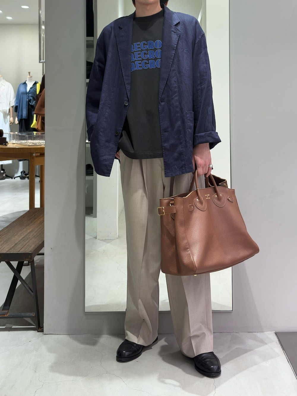 ブルー系のその他アウター、ベージュ系のその他パンツ、ブラウン系のトートバッグを着用したメンズの春コーディネートの2枚目の写真