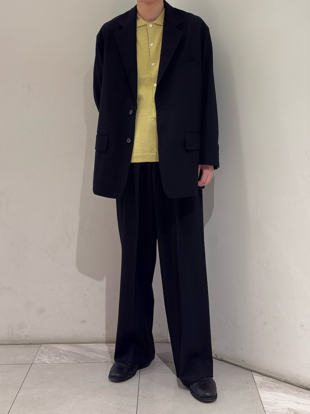 ブラック系のその他アウター、イエロー系のニット/セーター、ブラック系のその他パンツを着用したメンズの春コーディネートの2枚目の写真