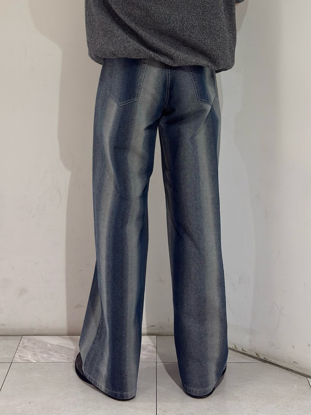 グレー系のニット/セーター、ブルー系のデニムパンツ、ブラック系のブーツを着用したメンズの春コーディネートの7枚目の写真
