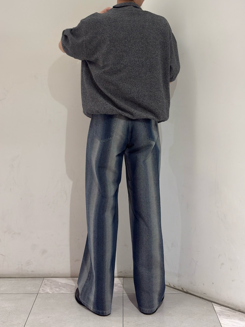 グレー系のニット/セーター、ブルー系のデニムパンツ、ブラック系のブーツを着用したメンズの春コーディネートの6枚目の写真
