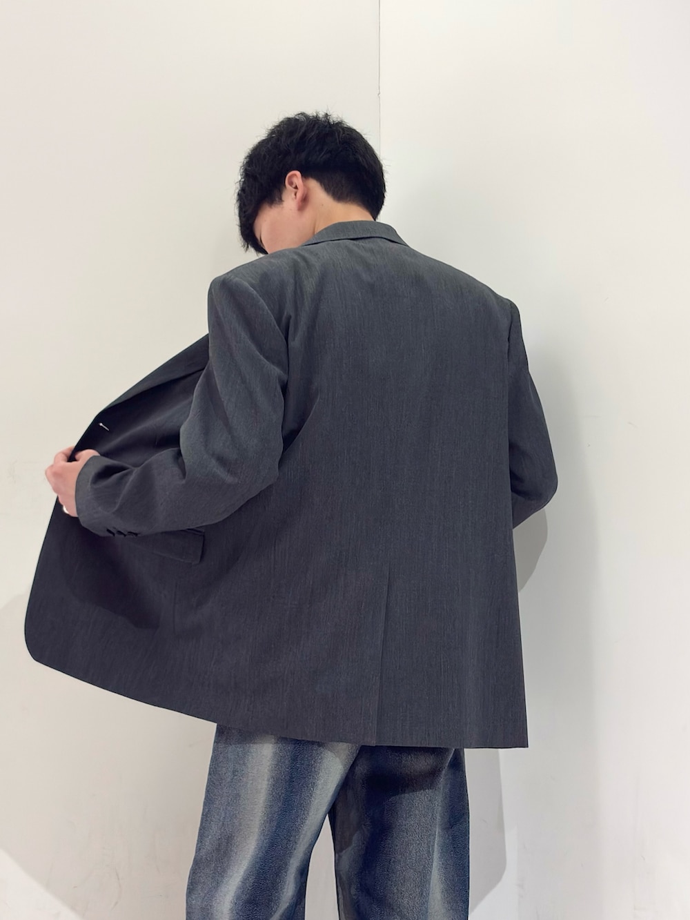 グレー系のテーラードジャケット、ホワイト系のニット/セーター、ブルー系のデニムパンツを着用したメンズの春コーディネートの5枚目の写真