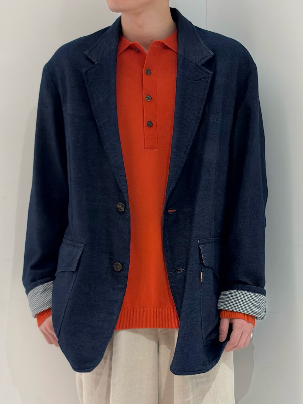 ブルー系のテーラードジャケット、オレンジ系のニット/セーター、ベージュ系のその他パンツを着用したメンズの春コーディネートの3枚目の写真