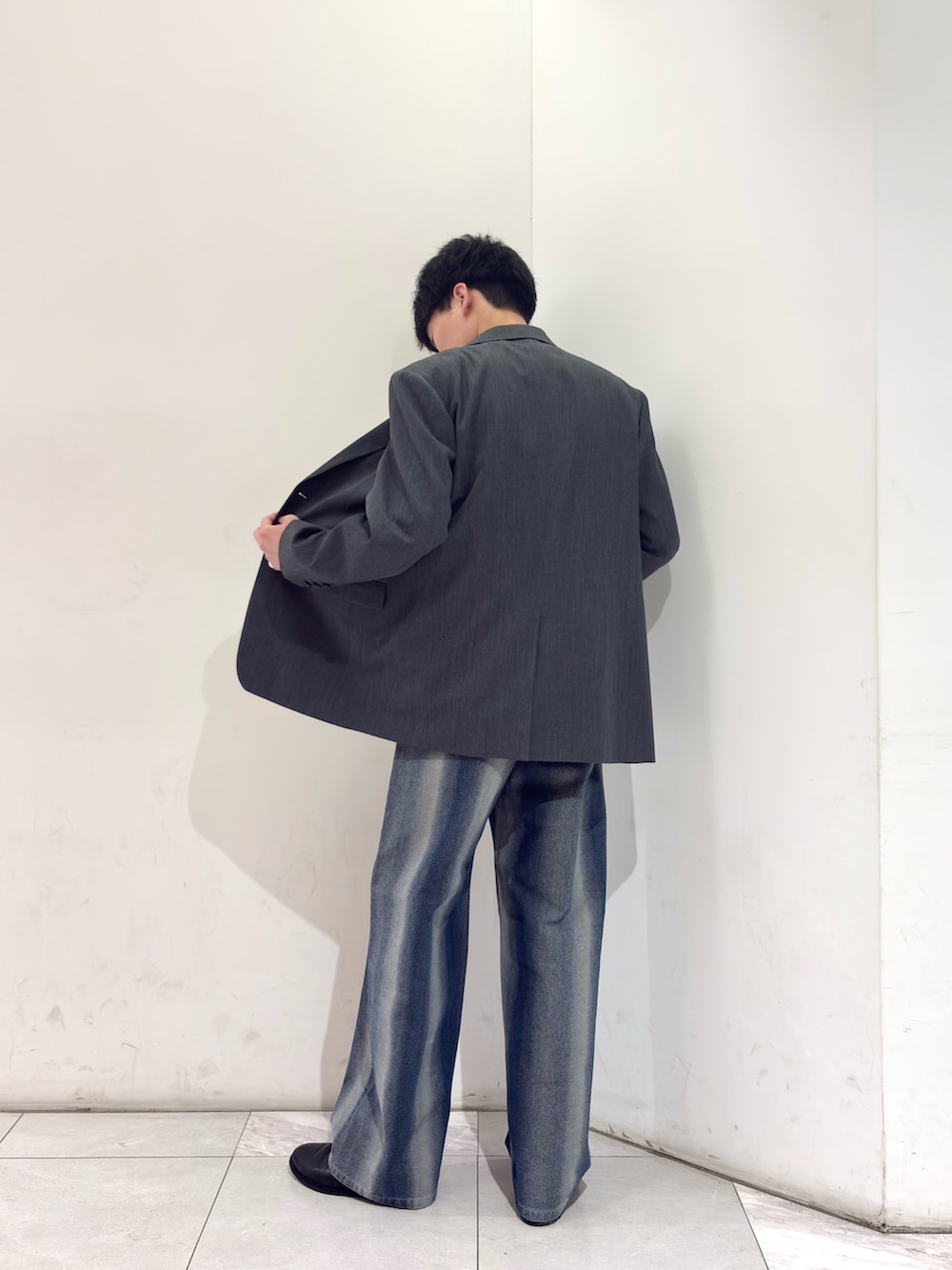 グレー系のテーラードジャケット、ホワイト系のニット/セーター、ブルー系のデニムパンツを着用したメンズの春コーディネートの4枚目の写真