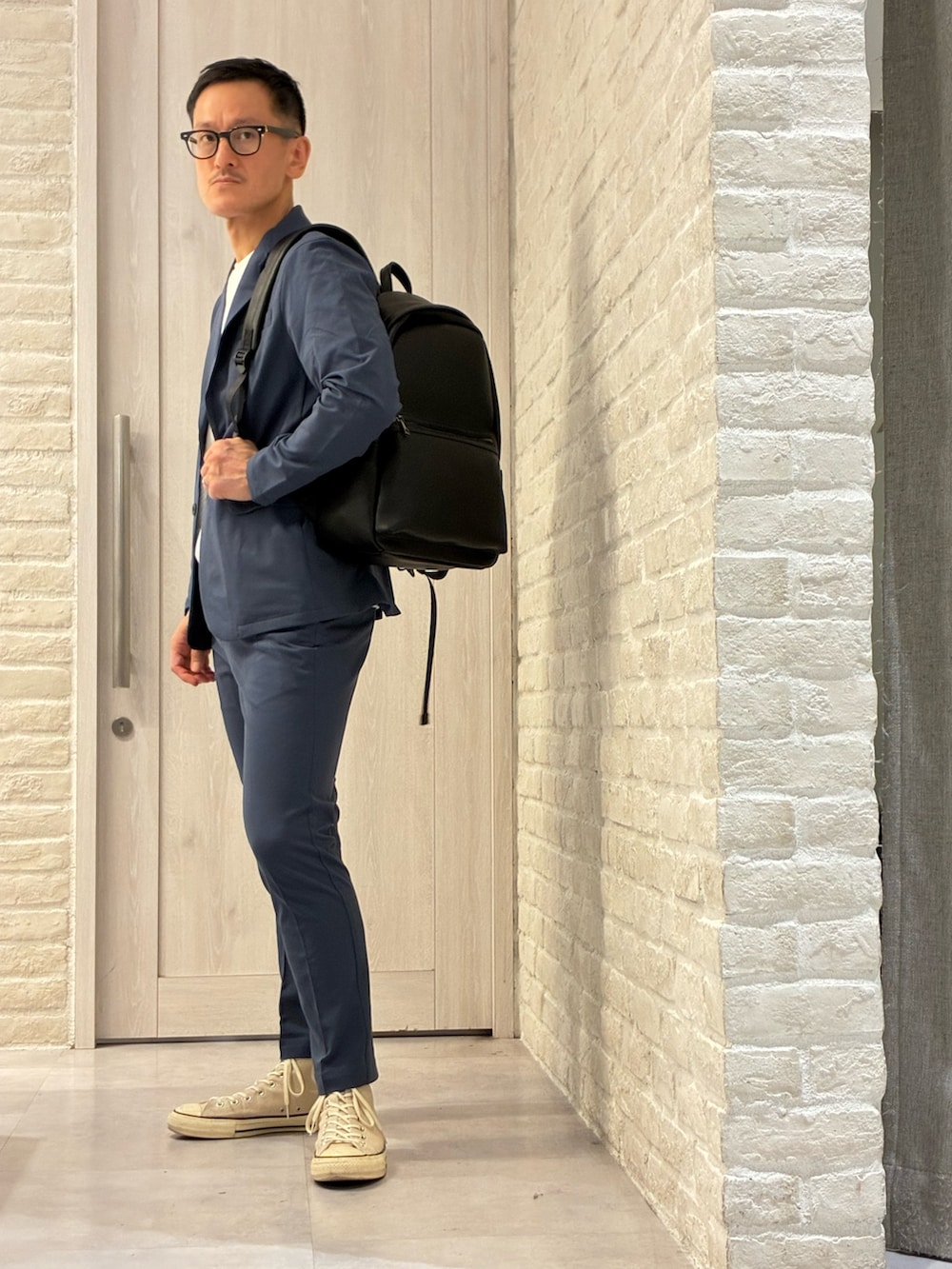 ブラック系のバックパック/リュック、ホワイト系のTシャツ/カットソー、ブルー系のテーラードジャケットを着用したメンズの春コーディネートの2枚目の写真