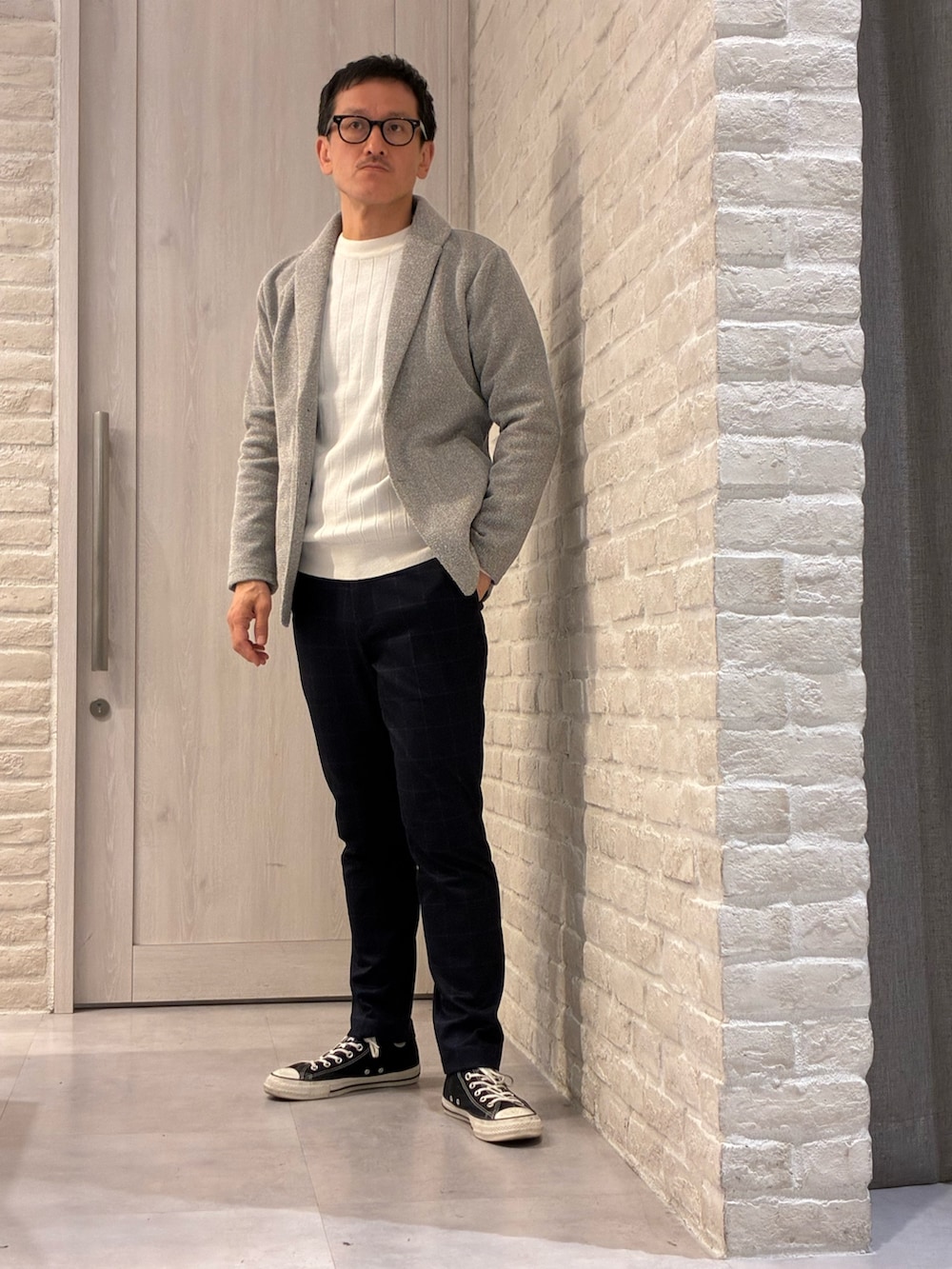 ブルー系のステンカラーコート、ブラウン系のブルゾン、ホワイト系のニット/セーターを着用したメンズの春コーディネートの2枚目の写真