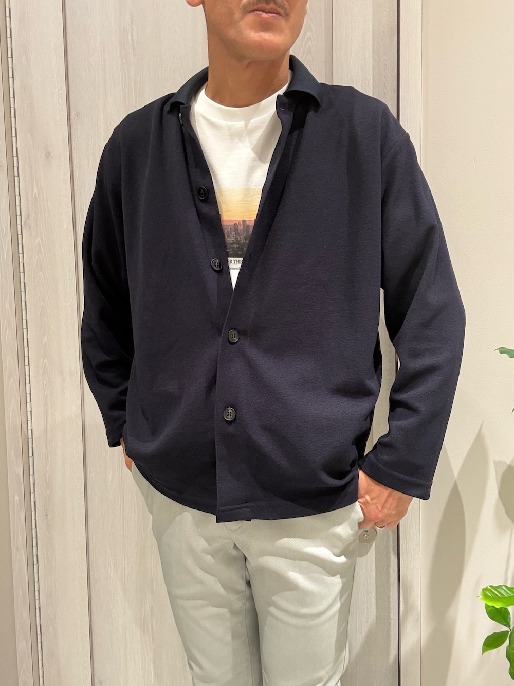 ブルー系のカーディガン/ボレロ、ホワイト系のTシャツ/カットソー、ベージュ系のスラックスを着用したメンズの秋コーディネートの3枚目の写真