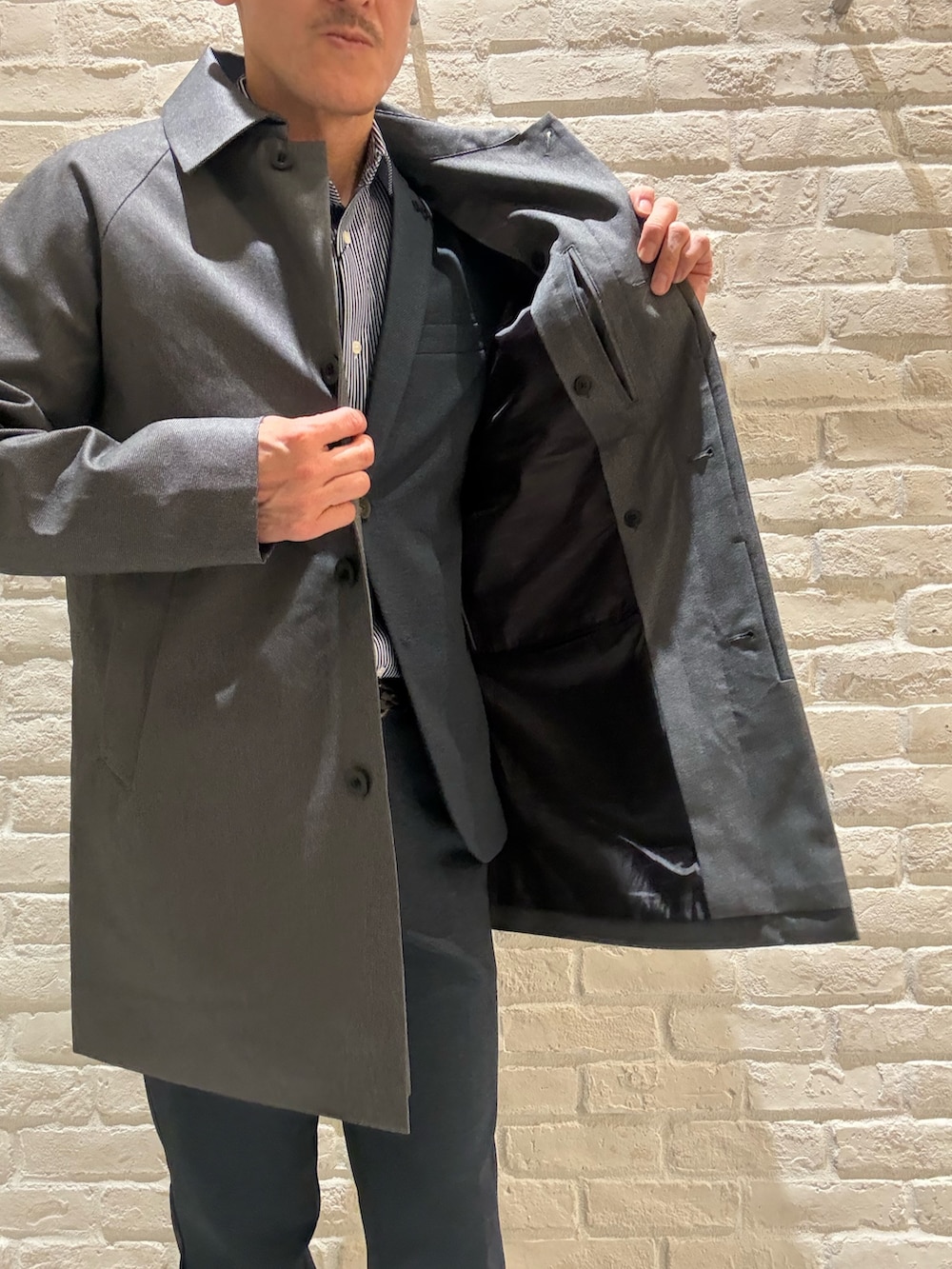 グレー系のステンカラーコート、ブルー系のテーラードジャケット、ブルー系のシャツ/ブラウスを着用したメンズの冬コーディネートの4枚目の写真