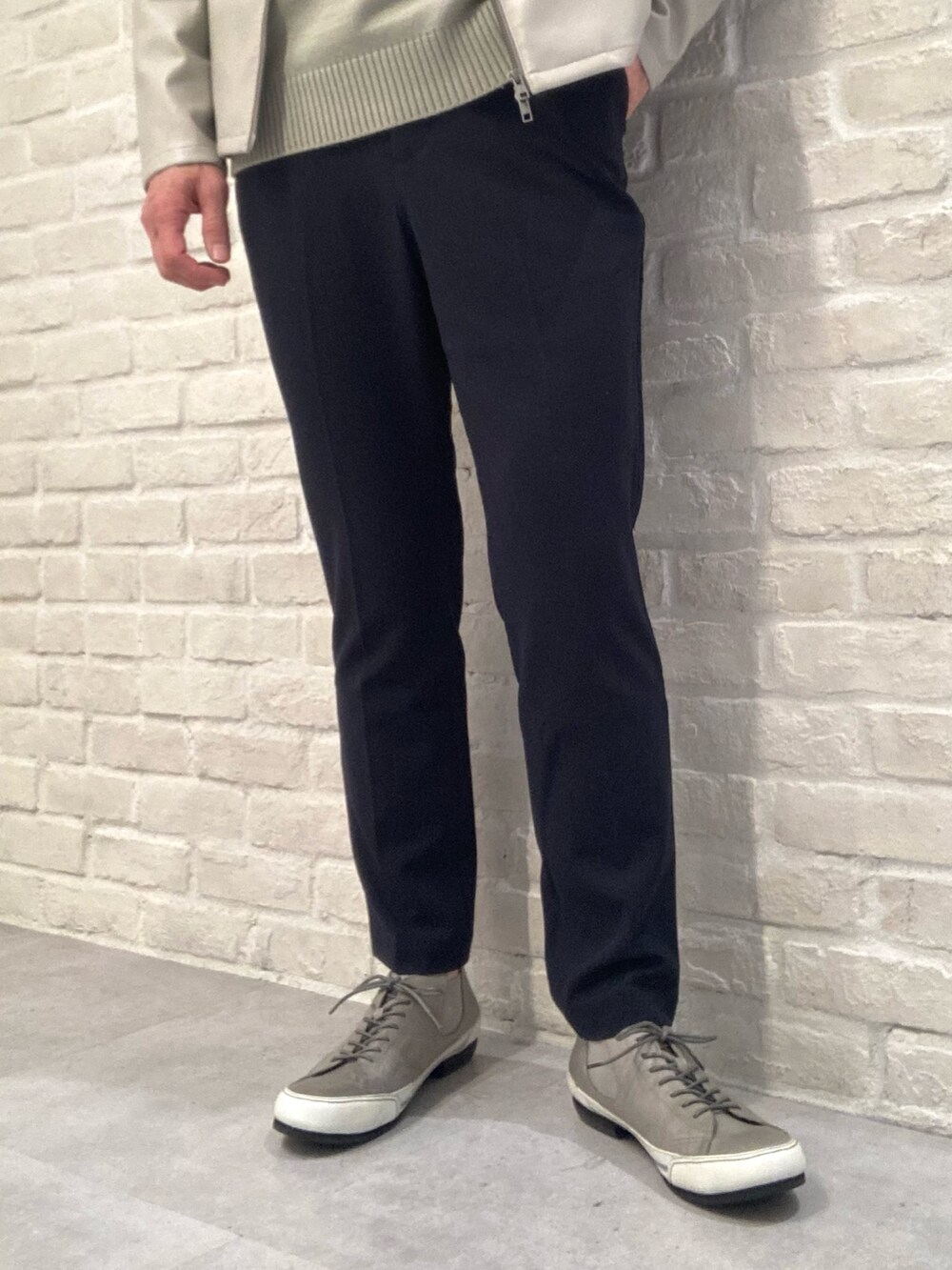 グレー系のライダースジャケット、グリーン系のニット/セーター、ブルー系のスラックスを着用したメンズの春コーディネートの4枚目の写真