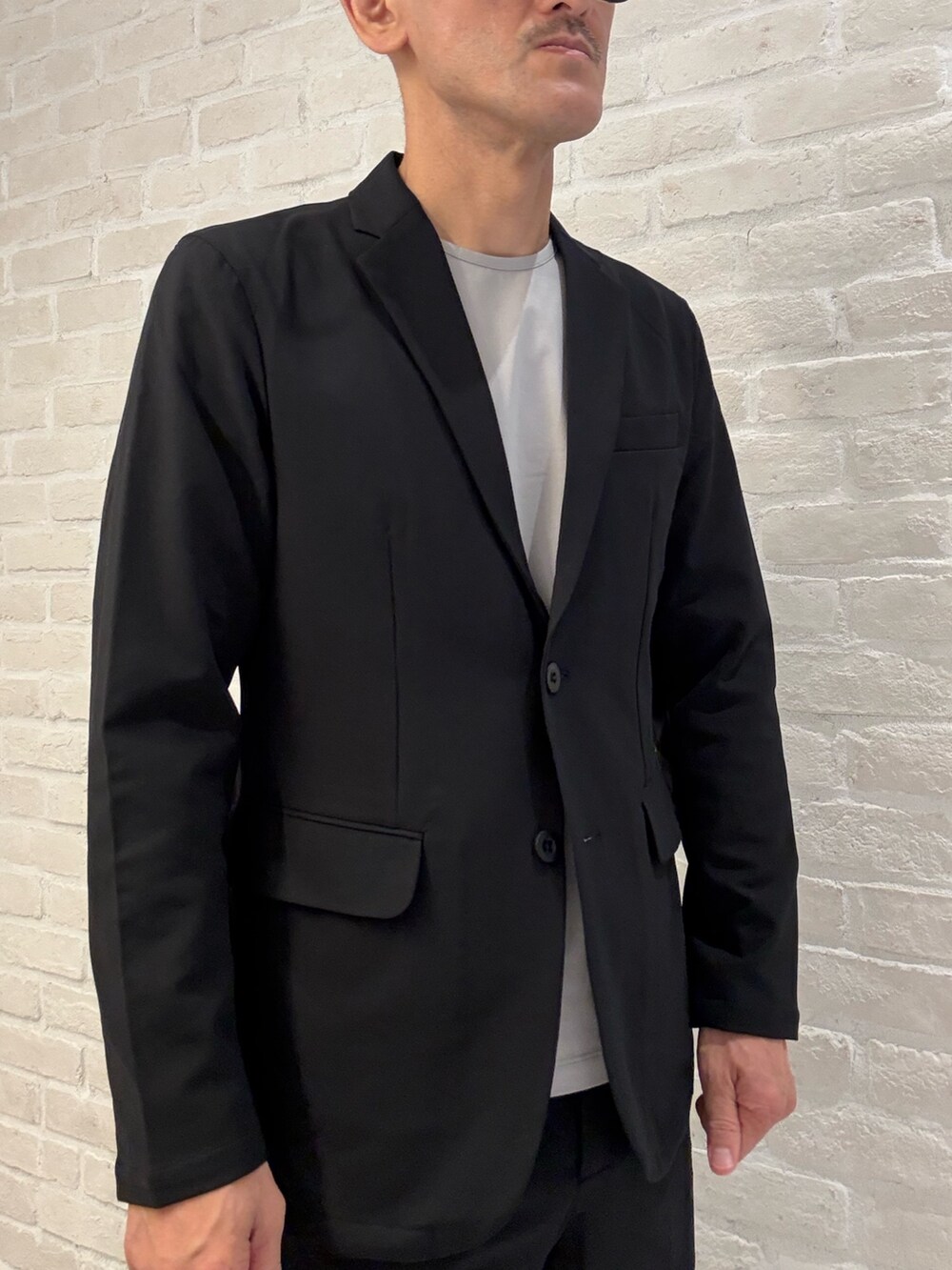 ベージュ系のTシャツ/カットソー、ブラック系のテーラードジャケット、ブラック系のセットアップを着用したメンズの秋コーディネートの3枚目の写真