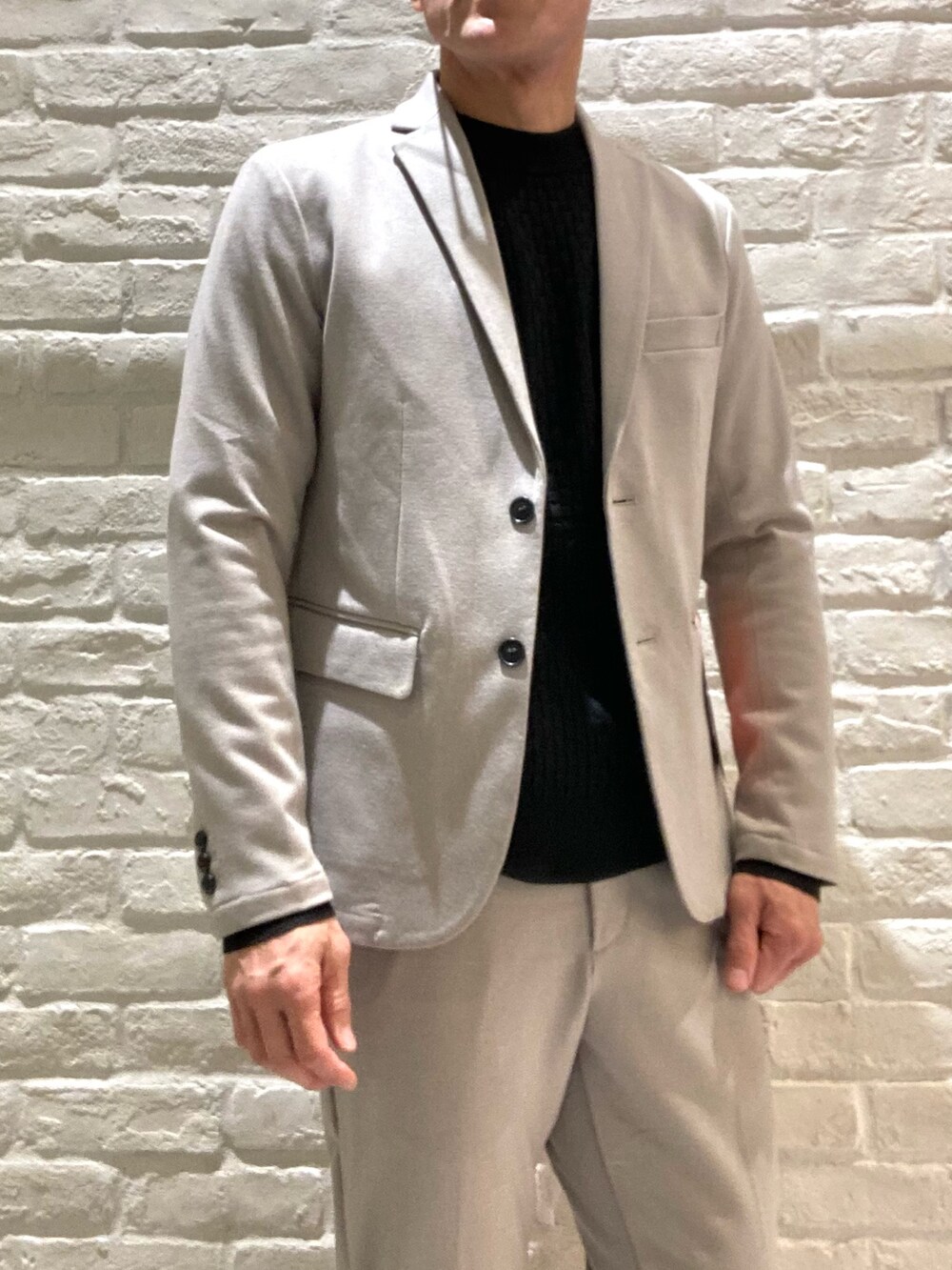 ベージュ系のセットアップ、ベージュ系のテーラードジャケット、ブラック系のニット/セーターを着用したメンズの冬コーディネートの4枚目の写真