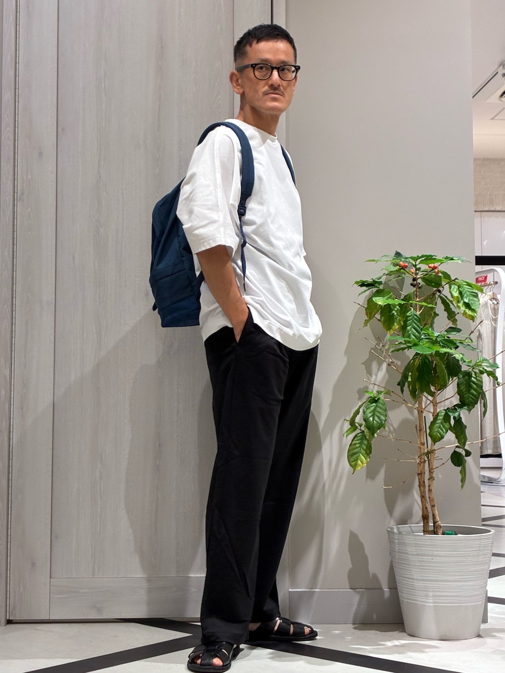 ブルー系のバックパック/リュック、ホワイト系のTシャツ/カットソー、ブラック系のその他パンツを着用したメンズの夏コーディネートの2枚目の写真