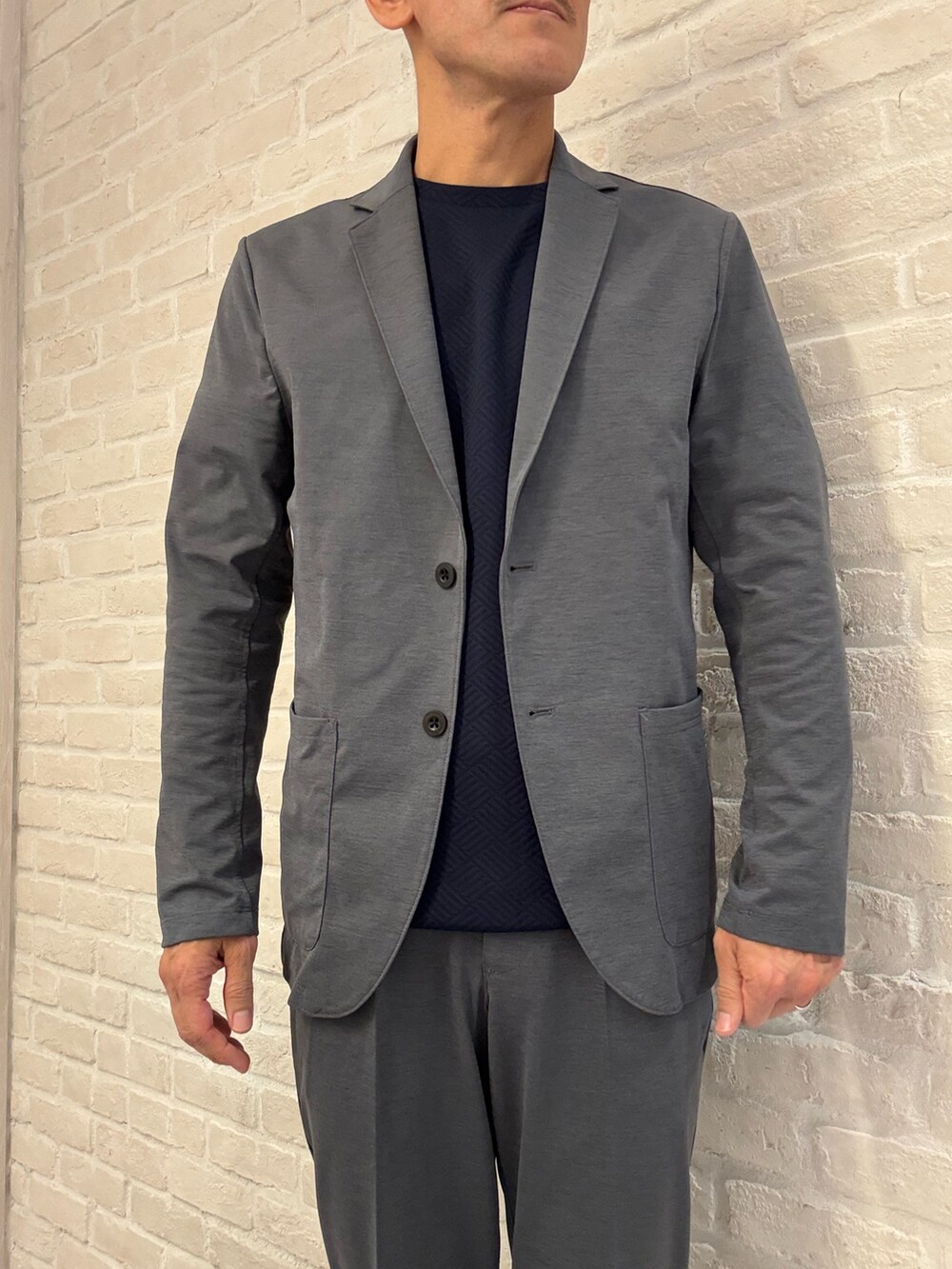 グレー系のテーラードジャケット、グレー系のスラックス、ブルー系のTシャツ/カットソーを着用したメンズの夏コーディネートの3枚目の写真