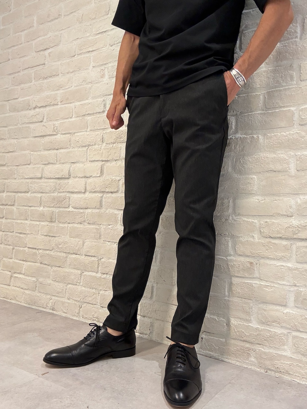 ブラック系のポロシャツ、ブラック系のスラックス、ブラック系のビジネスバッグを着用したメンズの夏コーディネートの4枚目の写真