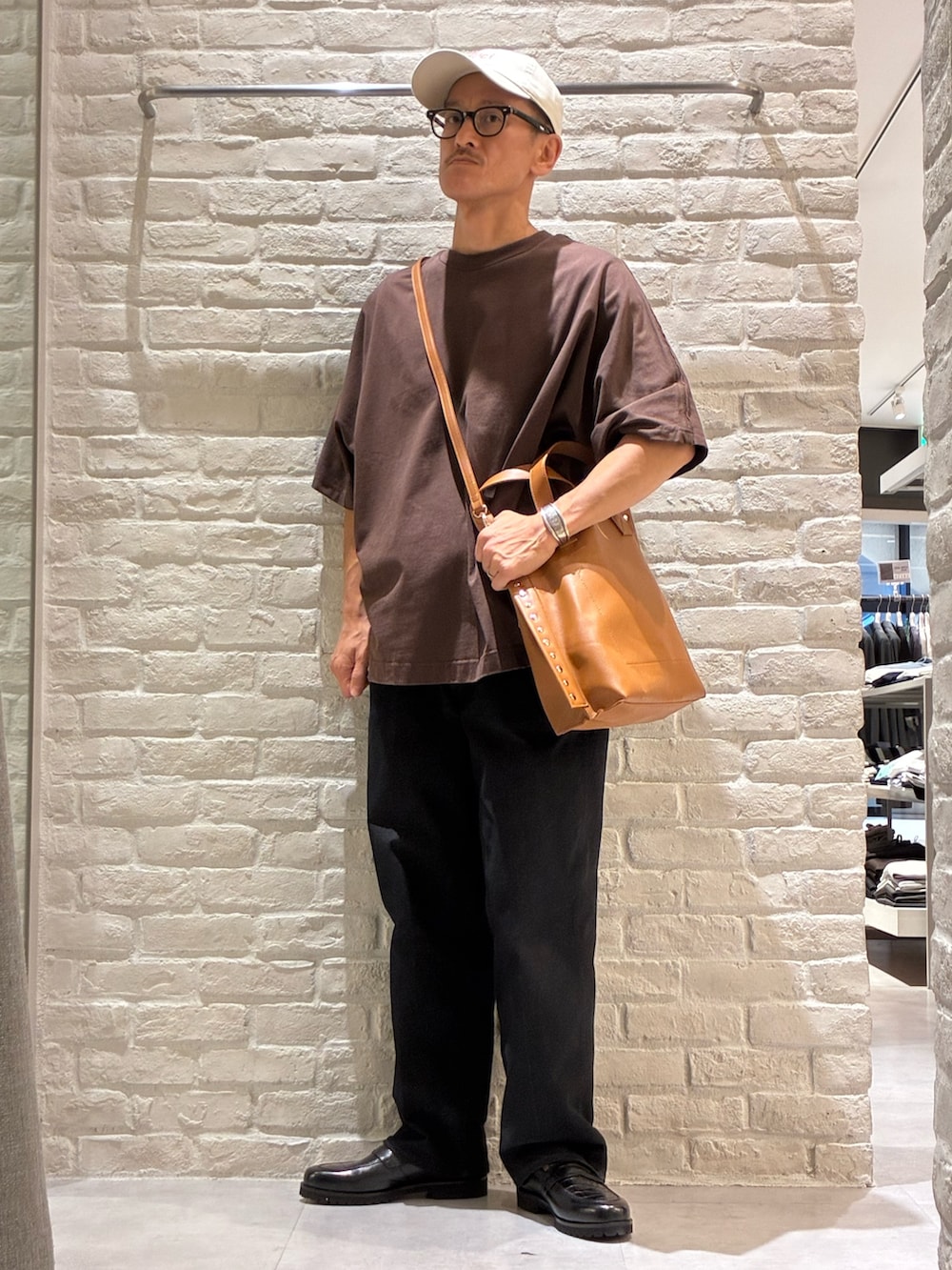 ブラウン系のTシャツ/カットソー、イエロー系のトートバッグ、ベージュ系のキャップを着用したメンズの夏コーディネートの2枚目の写真