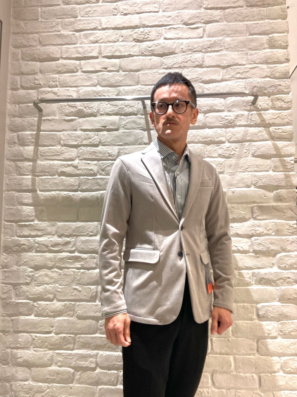 ベージュ系のテーラードジャケット、ブラック系のスラックス、ブラック系のシャツ/ブラウスを着用したメンズの冬コーディネートの2枚目の写真