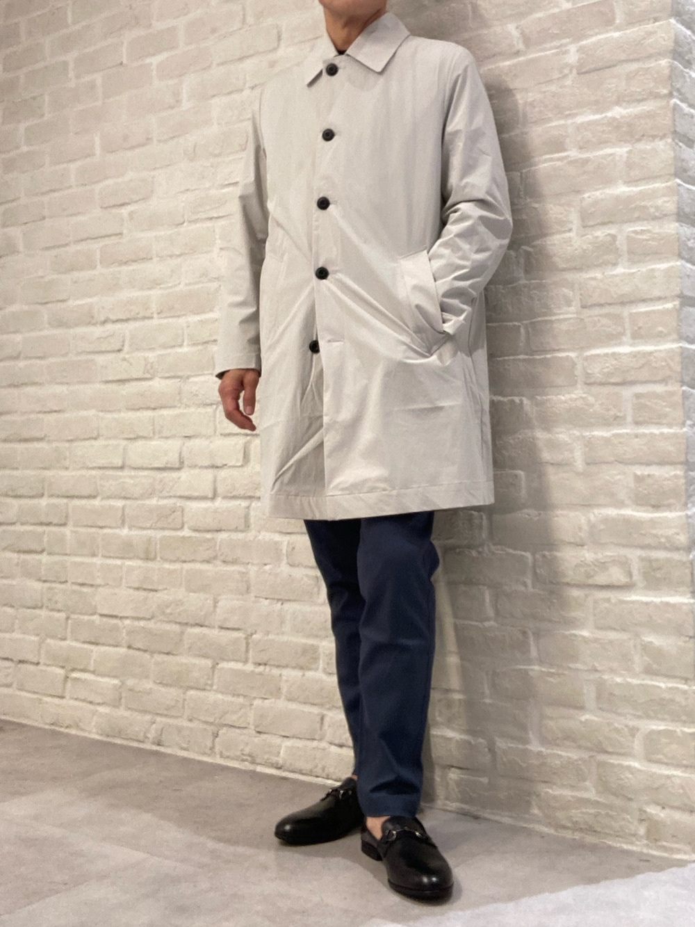 ベージュ系のステンカラーコート、ブルー系のテーラードジャケット、ブルー系のニット/セーターを着用したメンズの冬コーディネートの3枚目の写真