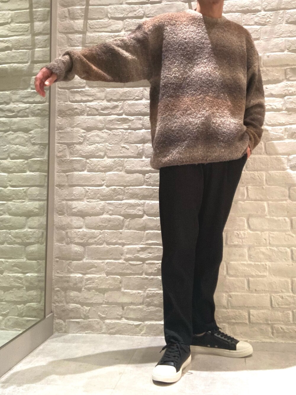 ブラック系のライダースジャケット、ブラウン系のニット/セーター、ブラック系のスラックスを着用したメンズの秋コーディネートの3枚目の写真