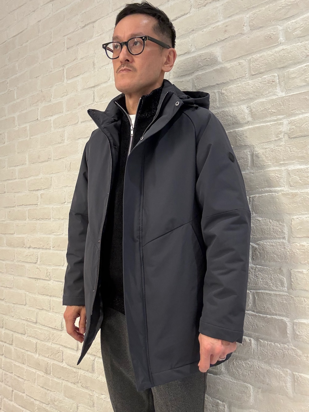 ブルー系のブルゾン、ブラック系のニット/セーター、ブラック系のスラックスを着用したメンズの冬コーディネートの2枚目の写真