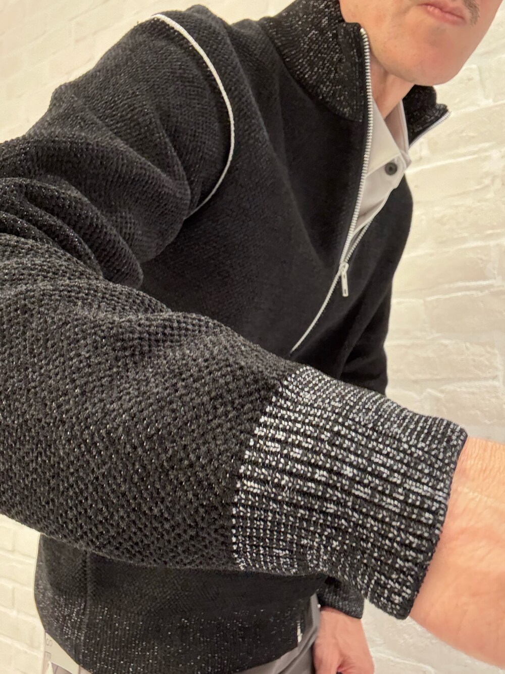 グレー系のチノパンツ、ブラック系のニット/セーター、ベージュ系のシャツ/ブラウスを着用したメンズの秋コーディネートの4枚目の写真