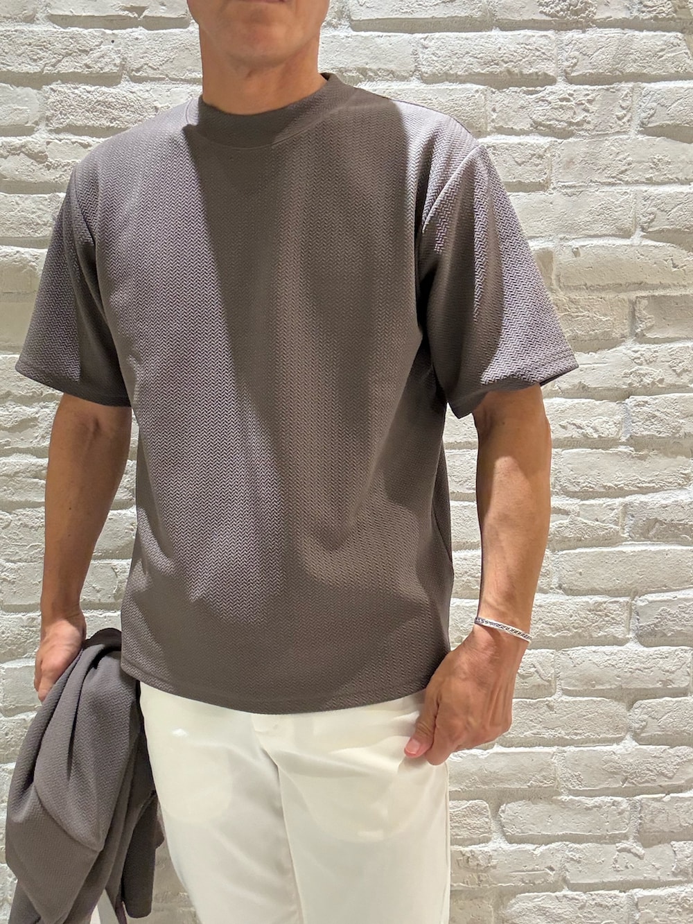 ブラウン系のカーディガン/ボレロ、ブラウン系のTシャツ/カットソー、ホワイト系のスラックスを着用したメンズの秋コーディネートの3枚目の写真