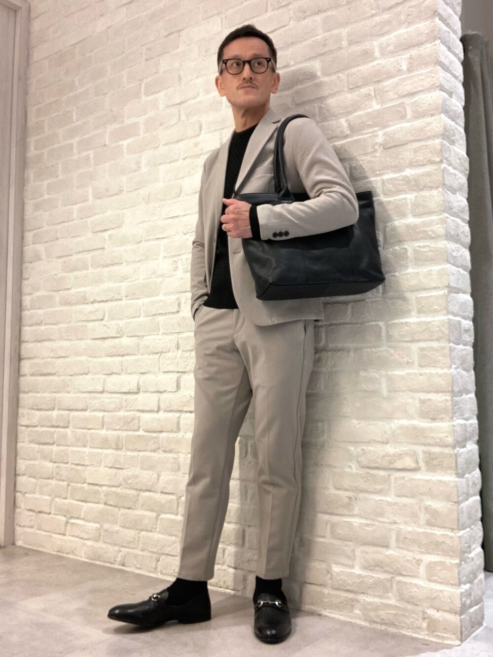 ベージュ系のセットアップ、ベージュ系のテーラードジャケット、ブラック系のニット/セーターを着用したメンズの冬コーディネートの2枚目の写真