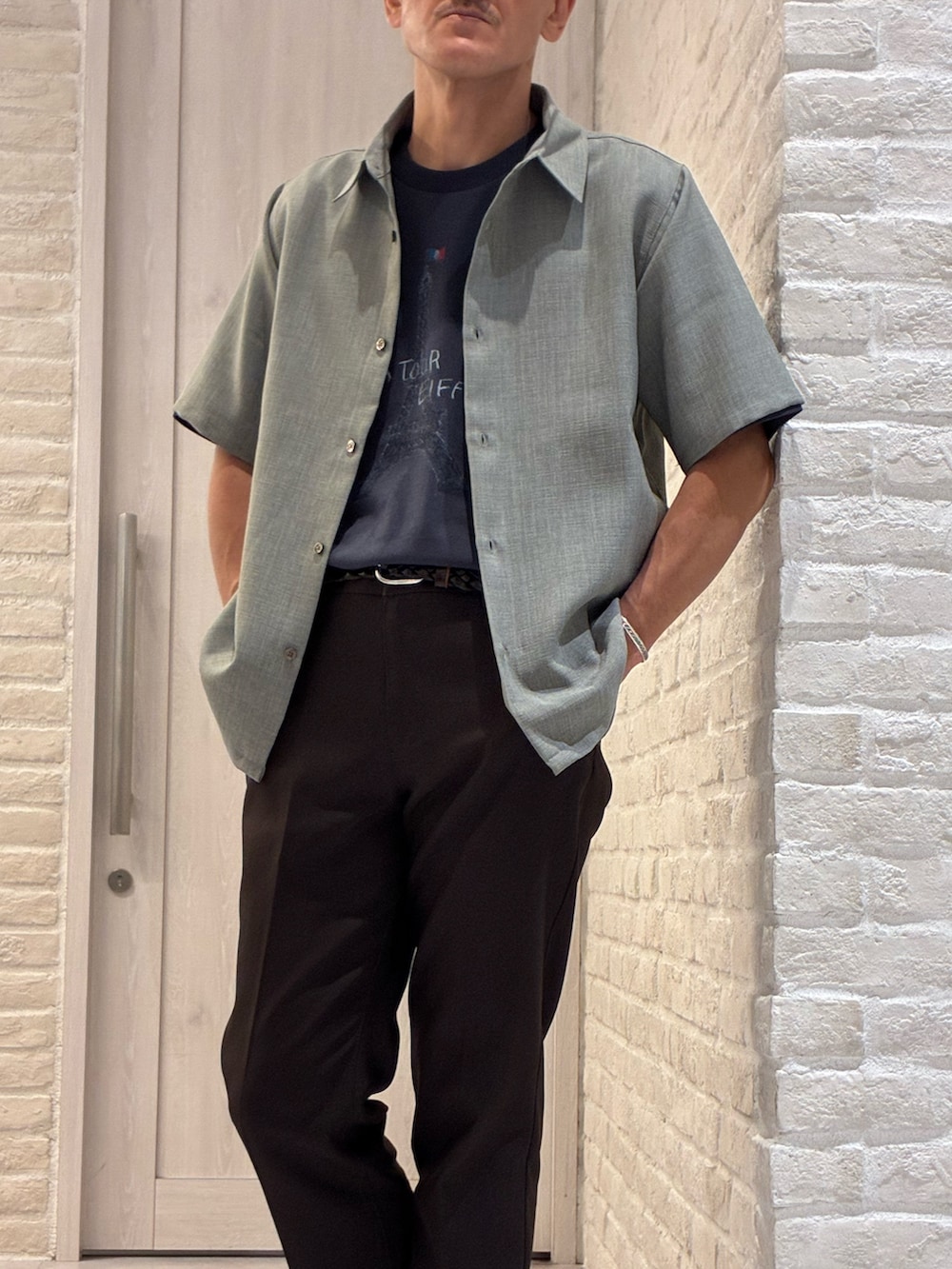 グリーン系のシャツ/ブラウス、ブラック系のTシャツ/カットソー、ブラウン系のスラックスを着用したメンズの夏コーディネートの2枚目の写真