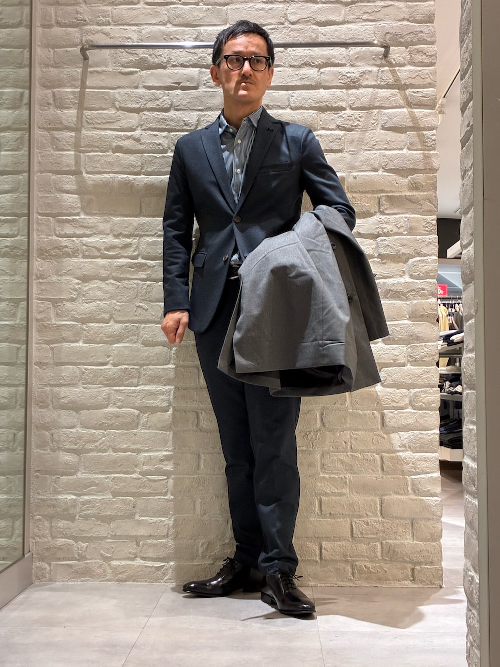 グレー系のステンカラーコート、ブルー系のテーラードジャケット、ブルー系のシャツ/ブラウスを着用したメンズの冬コーディネートの3枚目の写真