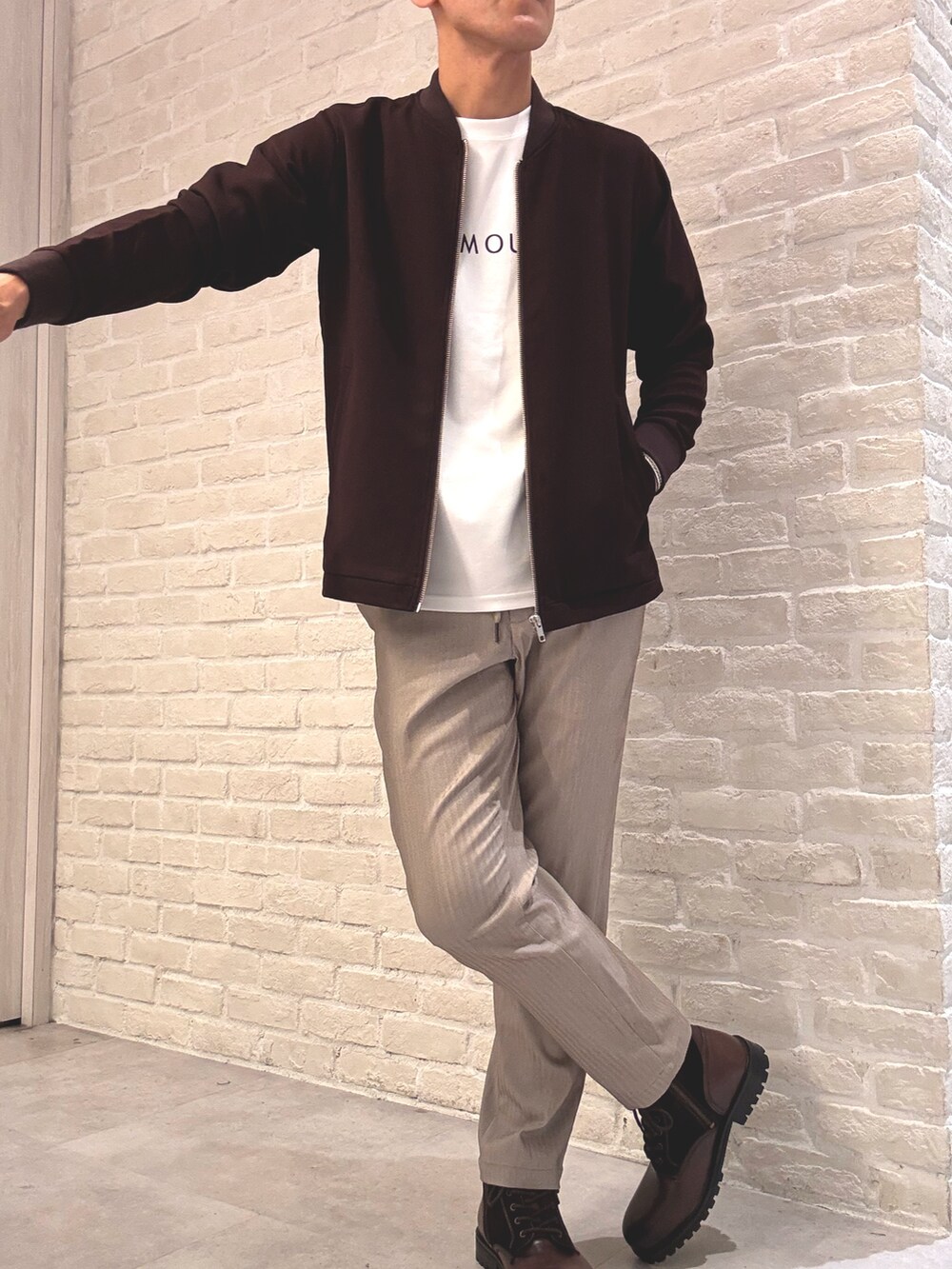 レッド系のブルゾン、ホワイト系のTシャツ/カットソー、ベージュ系のスラックスを着用したメンズの秋コーディネートの2枚目の写真