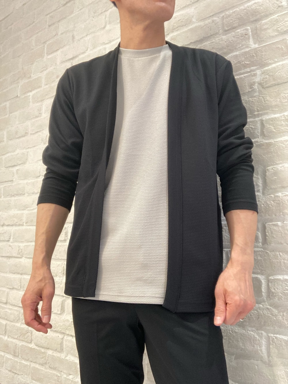 ブラック系のカーディガン/ボレロ、ベージュ系のTシャツ/カットソー、ブラック系のスラックスを着用したメンズの春コーディネートの3枚目の写真