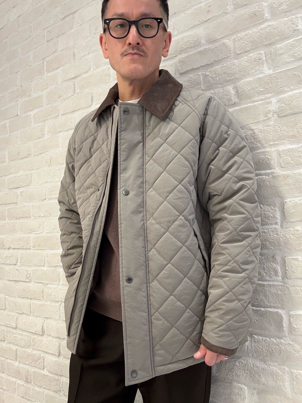 ブラウン系のブルゾン、ベージュ系のニット/セーター、ブラウン系のスラックスを着用したメンズの冬コーディネートの3枚目の写真