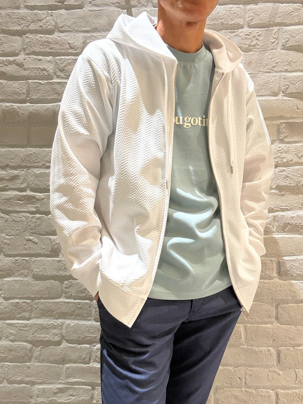 ホワイト系のパーカー、グリーン系のTシャツ/カットソー、ブルー系のスラックスを着用したメンズの春コーディネートの3枚目の写真